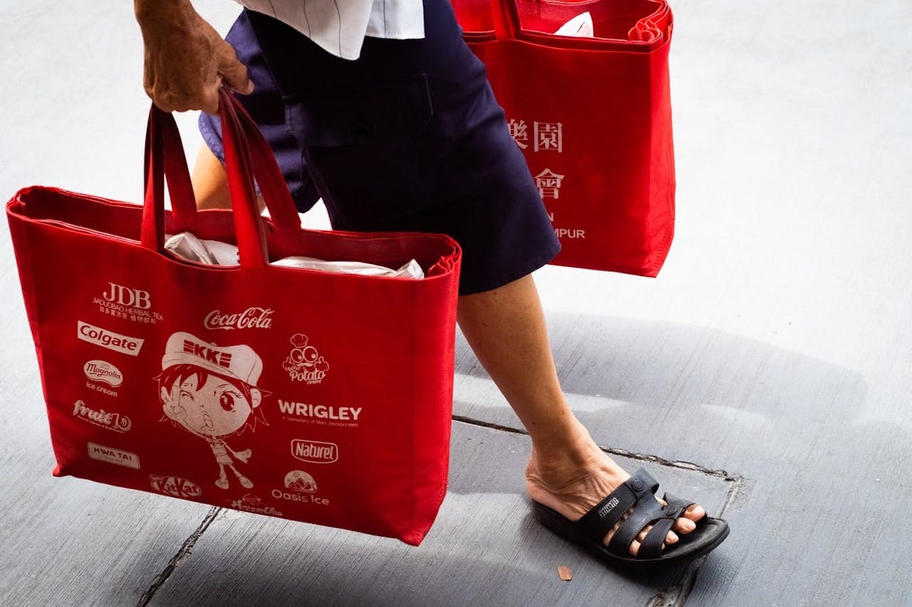 man walking with red shopping bags