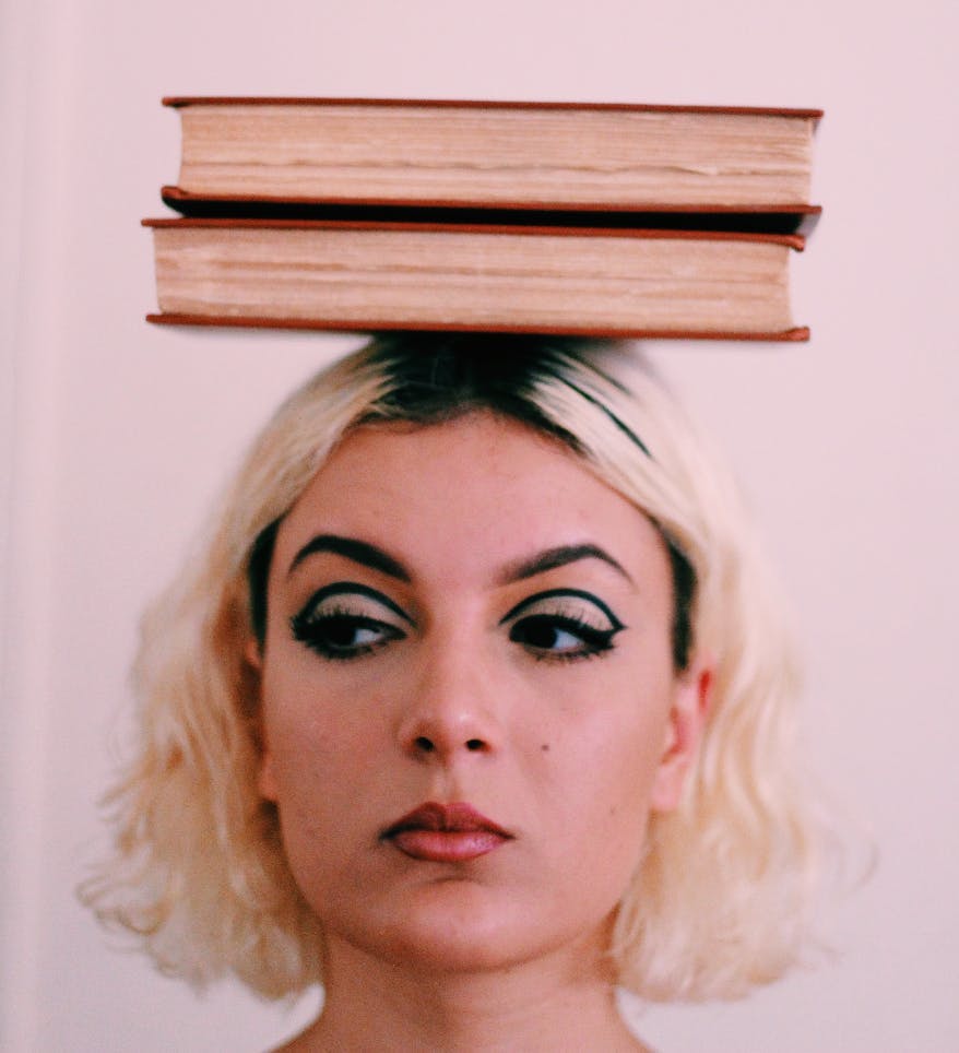 Women wearing eyeliner and balancing books on her head: Beauty Trends in 2024: Growth and Personalization
